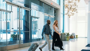 A modern lobby with glass doors, a staircase, and a seating area with cushions. - Virginia Guesthouse Hotel (Charlottesville)