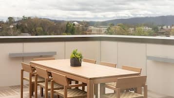 A wooden deck with a table and chairs, overlooking a cityscape.