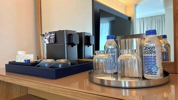 Minibar de habitación de hotel con una máquina de café, una bandeja con tazas y botellas de agua.