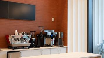 A modern bar area with a wooden counter, espresso machines, and a large window providing a view.