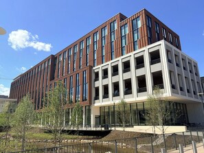A modern building with a mix of brick and glass facade, multiple floors, and a flat roof. - Virginia Guesthouse Hotel (Charlottesville)