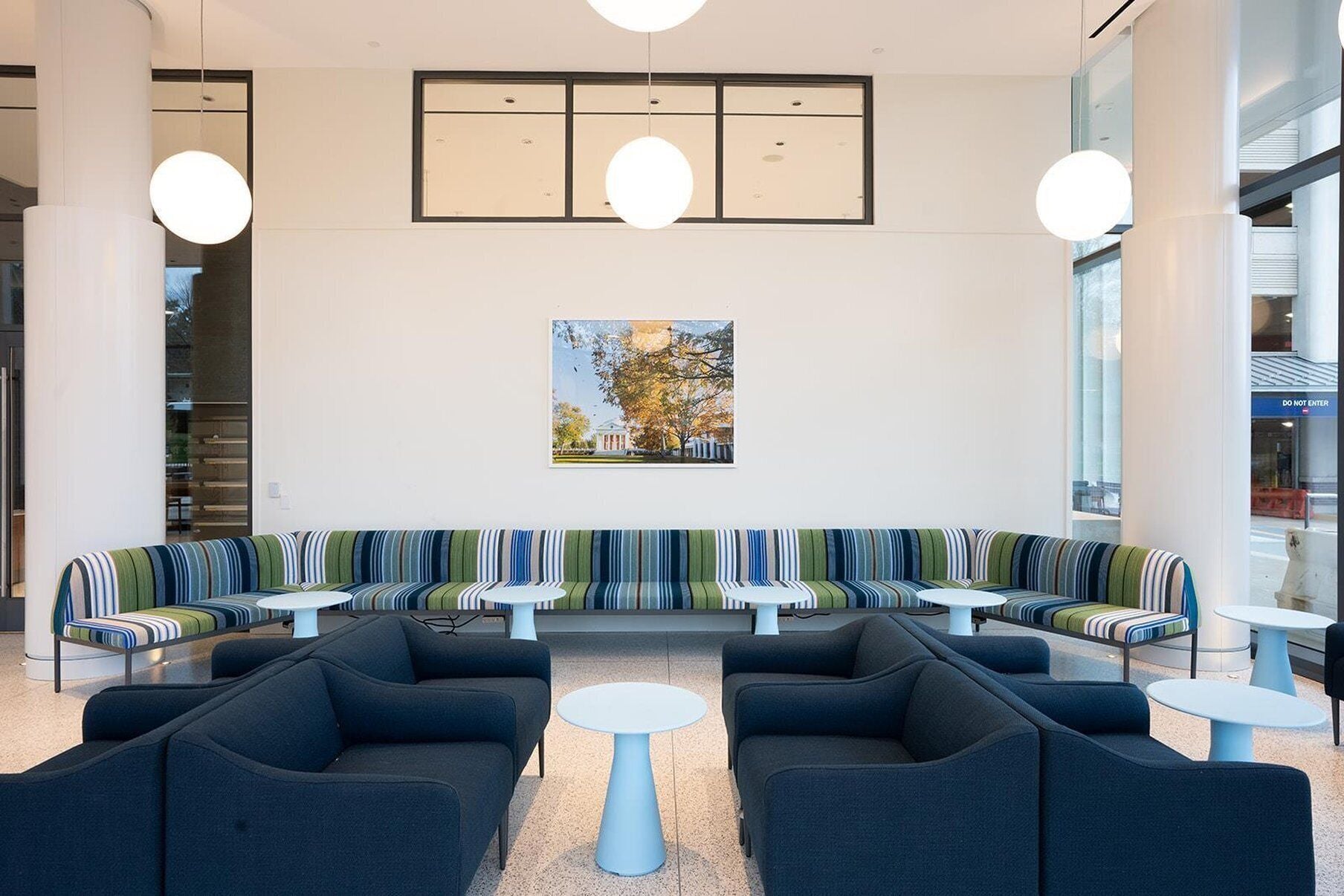 A modern waiting area with a bench seating arrangement, a central table, and pendant lighting.