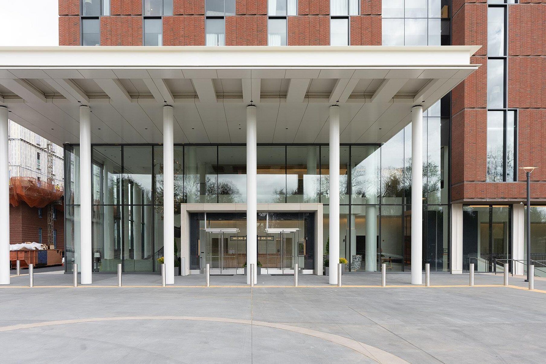 Una entrada moderna de edificio con un corredor cubierto, puertas de cristal y fachada de ladrillo.