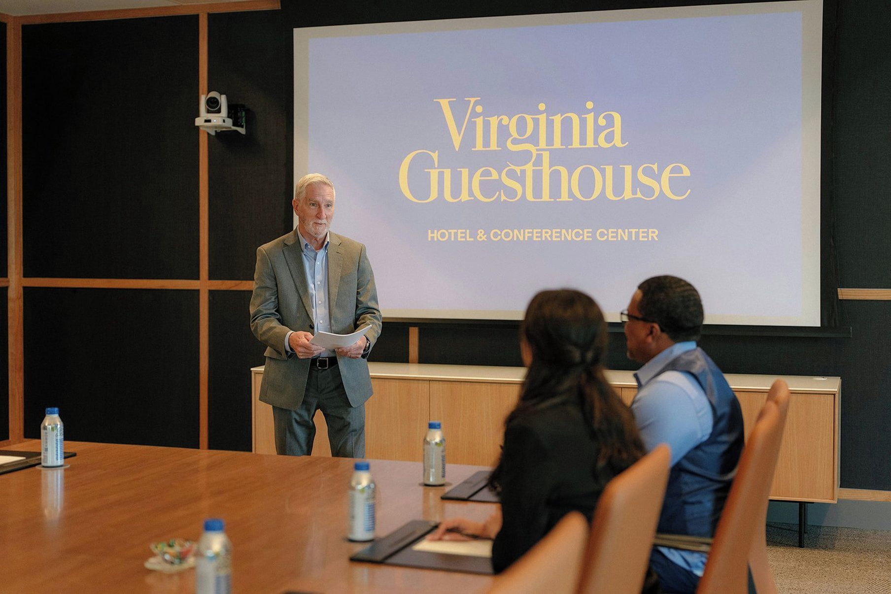 A conference room with a presentation screen displaying 'Virginia Guesthouse HOTEL & CONFERENCE CENTER'.