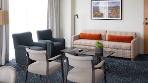 A hotel room with a sofa, two armchairs, a dining table, and a lamp. - Virginia Guesthouse Hotel (Charlottesville)