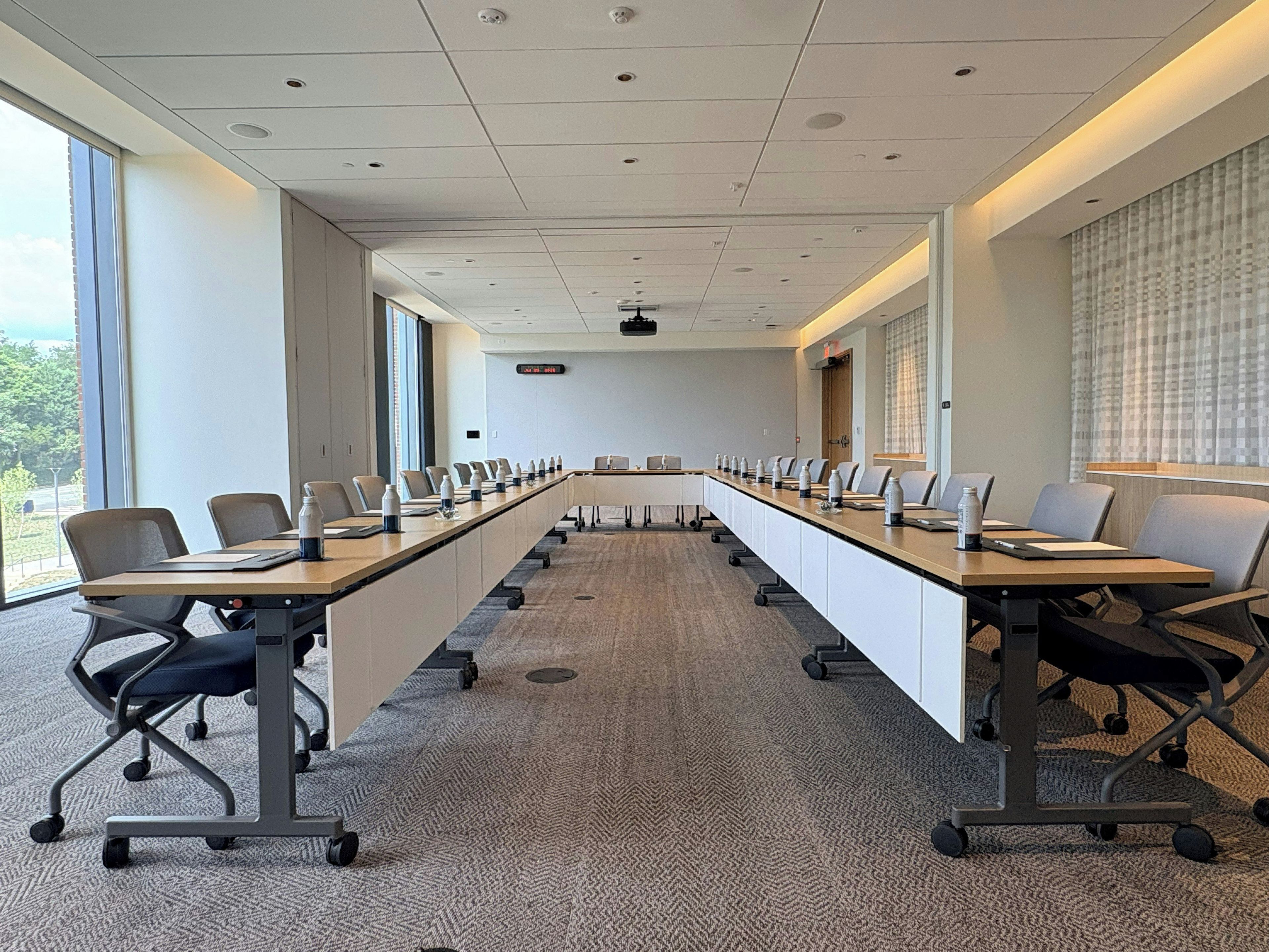 A conference room with a long table, chairs, and a projector screen.