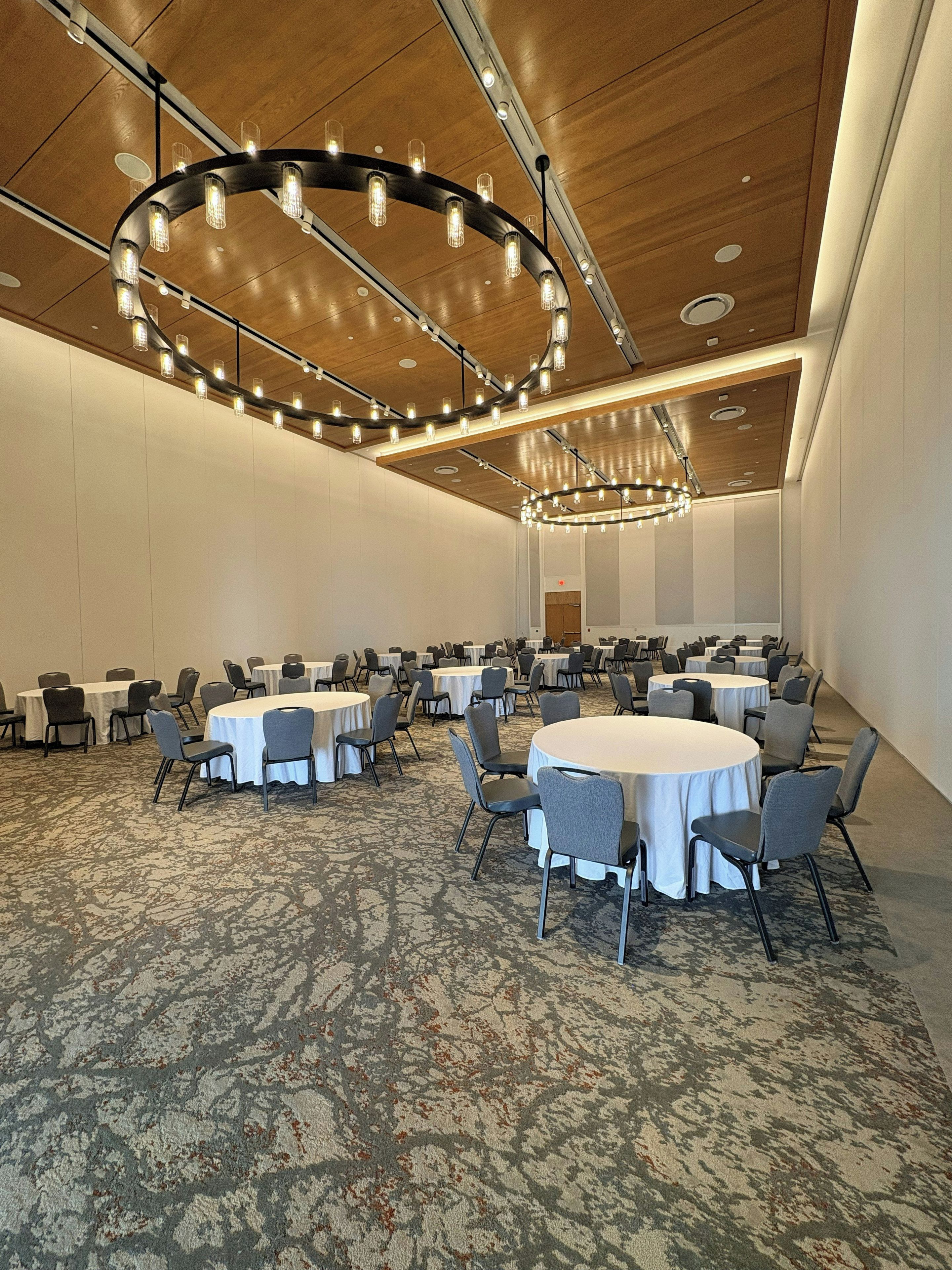 A conference room with round tables, chairs, and modern lighting fixtures.