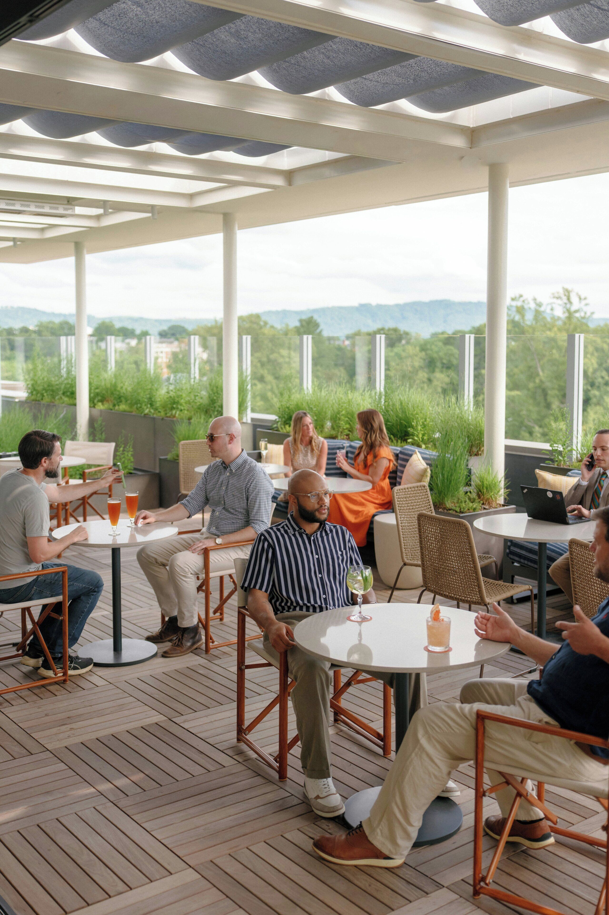 A covered outdoor seating area with tables and chairs, overlooking a scenic landscape.