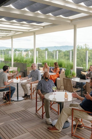 A covered outdoor seating area with tables and chairs, overlooking a scenic landscape. - Virginia Guesthouse Hotel (Charlottesville)
