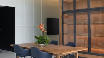 A modern meeting room with a wooden table, four chairs, and a potted plant.