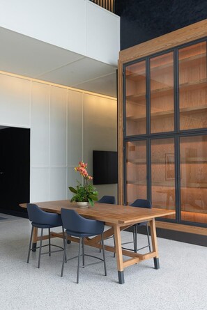 A modern meeting room with a wooden table, four chairs, and a potted plant. - Virginia Guesthouse Hotel (Charlottesville)