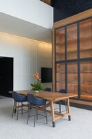 Una sala de reuniones moderna con una mesa de madera, cuatro sillas y una planta en maceta.