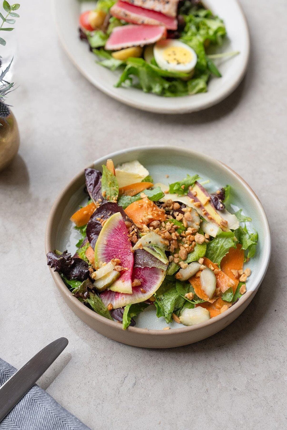A bowl of salad with various vegetables and nuts.