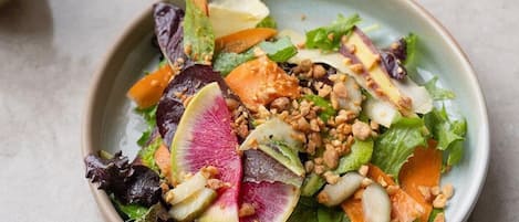A bowl of salad with various vegetables and nuts.