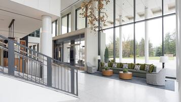 Un hall d’entrée spacieux avec un escalier, un coin salon et de grandes fenêtres.