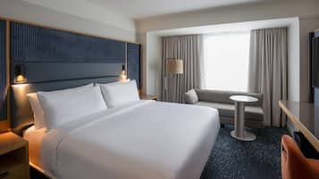 Une chambre d’hôtel avec un grand lit, un canapé, une petite table ronde et un téléviseur.