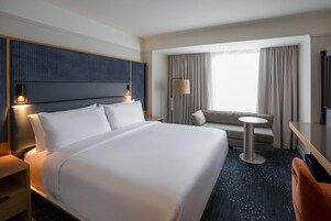 Una habitación de hotel con una cama grande, un sofá, una mesita redonda y un televisor.