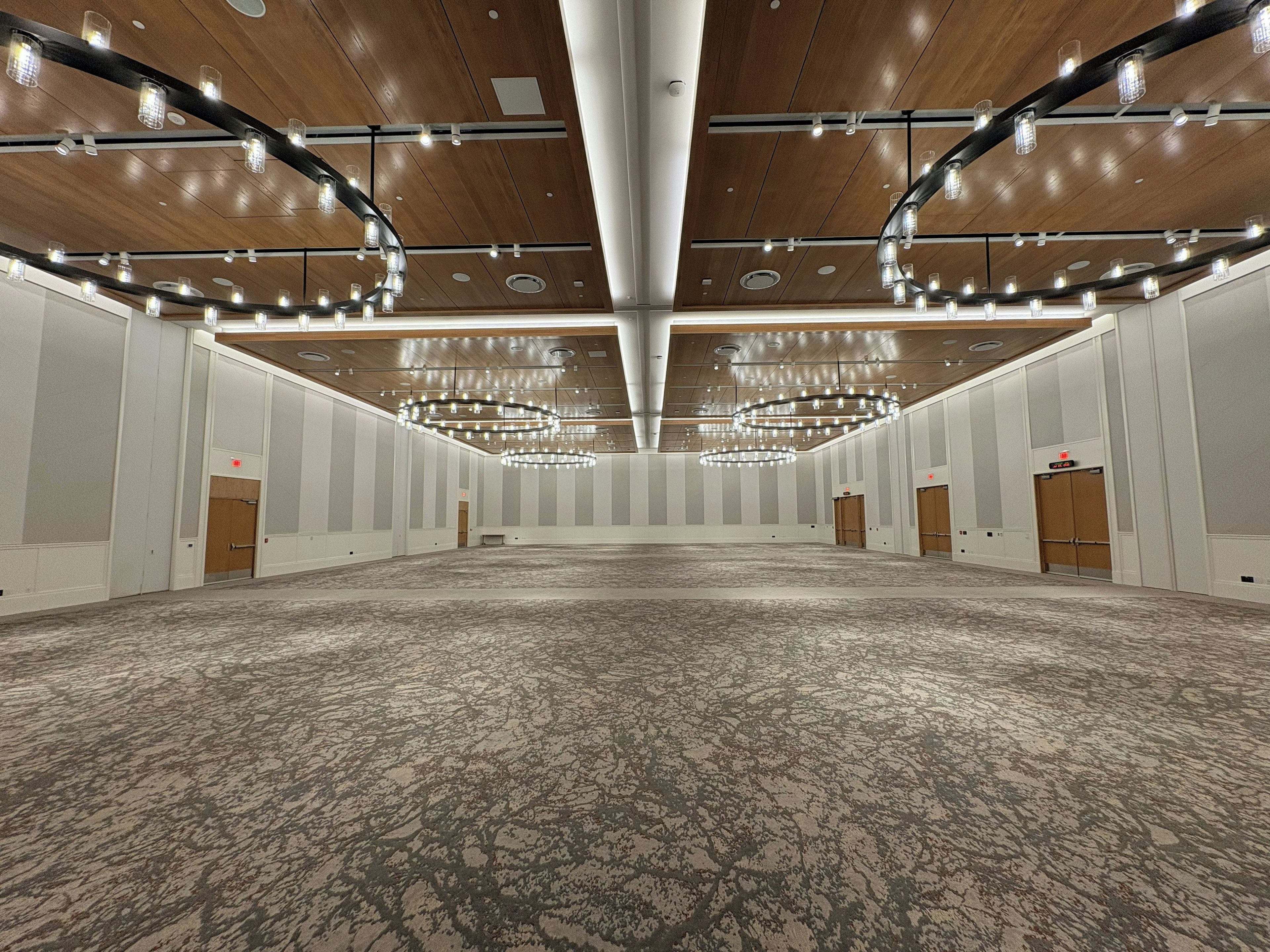 A large conference room with a high ceiling, multiple chandeliers, and a patterned carpet.