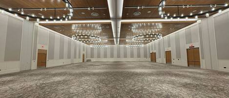 A large conference room with a high ceiling, multiple chandeliers, and a patterned carpet.