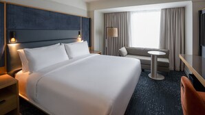 A hotel room with a large bed, a desk, a chair, a lamp, and a TV. - Virginia Guesthouse Hotel (Charlottesville)