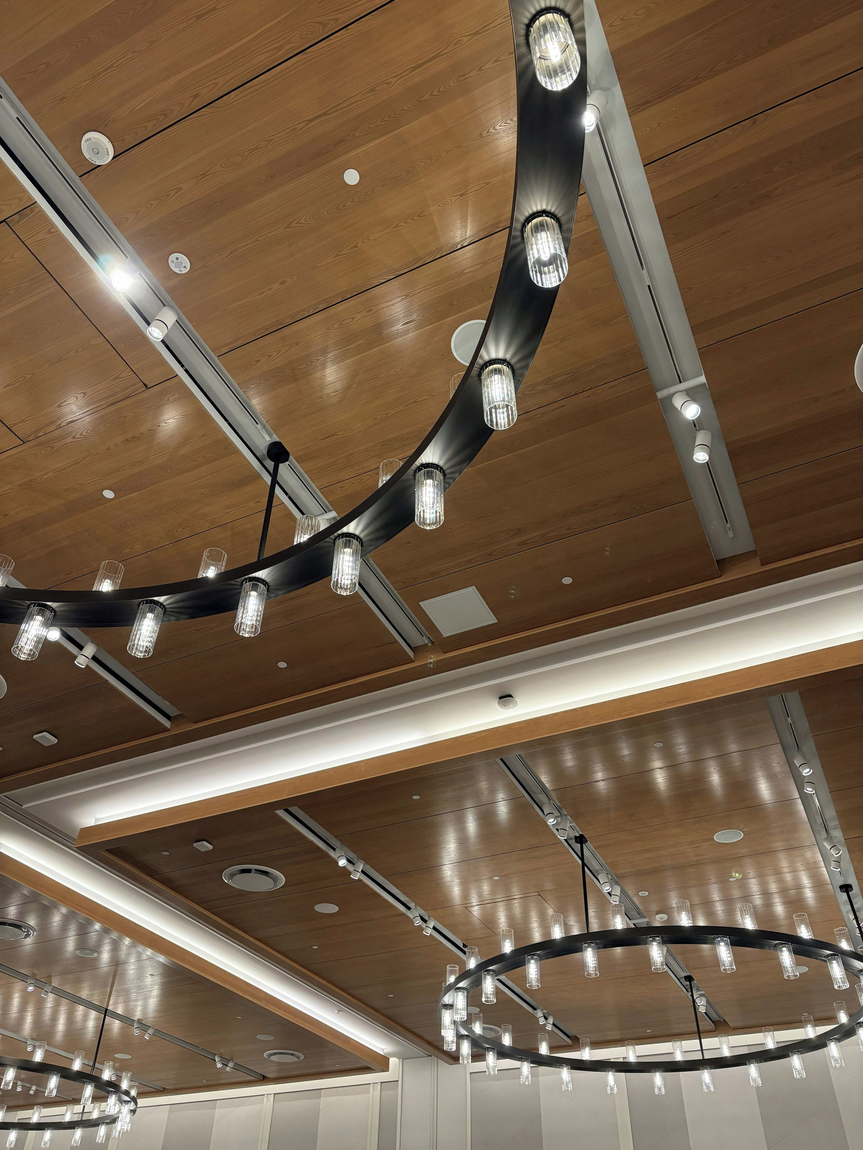 Eine moderne Decke mit mehreren Leuchten, darunter ein markantes, gebogenes Design und verschiedene geradlinige Elemente.