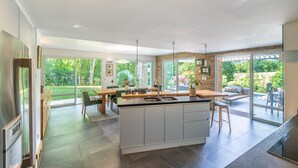 Una cocina moderna con una isla grande, electrodomésticos integrados y un comedor con vistas al exterior.