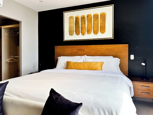 A modern hotel room with a wooden headboard, white bedding, and a single gold-colored pillow.
