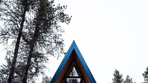 A triangular wooden cabin with large windows, surrounded by snow and trees. - Modern A-Frame • Forest Views + Hot Tub • 30 min to Yellowstone (Island Park)