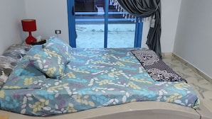 Een bed met bloemenbedekte lakens, een rode lamp en een raam met gordijnen.