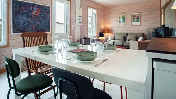 Una cocina moderna con una isla blanca, sillas de madera y una mesa de comedor preparada para cuatro.