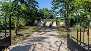 A gravel driveway leading to a house with a metal gate. - La Salamandre - maison avec jacuzzi (Selles-sur-Cher)