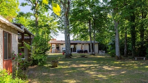 A house with a patio area, surrounded by trees and a grassy yard. - La Salamandre - maison avec jacuzzi (Selles-sur-Cher)