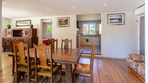 A spacious dining area with a wooden table and chairs, a kitchen with a washing machine, and a sofa with a floral pattern. - La Salamandre - maison avec jacuzzi (Selles-sur-Cher)