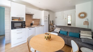 A modern kitchen with white cabinets, a microwave, and a dining table with a woven basket.