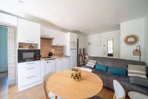 Une cuisine moderne avec des meubles blancs, un four à micro-ondes et une table à manger agrémentée d’un panier en osier.