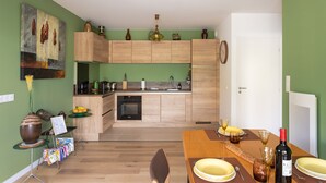 Eine moderne Küche mit Holzschnitzschränken, einem Esstisch für vier Personen und einer grünen Wand mit einem Gemälde.