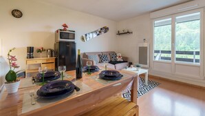 Een moderne keuken met een eethoek voor vier personen, voorzien van een groot raam, een magnetron en een koelkast.
