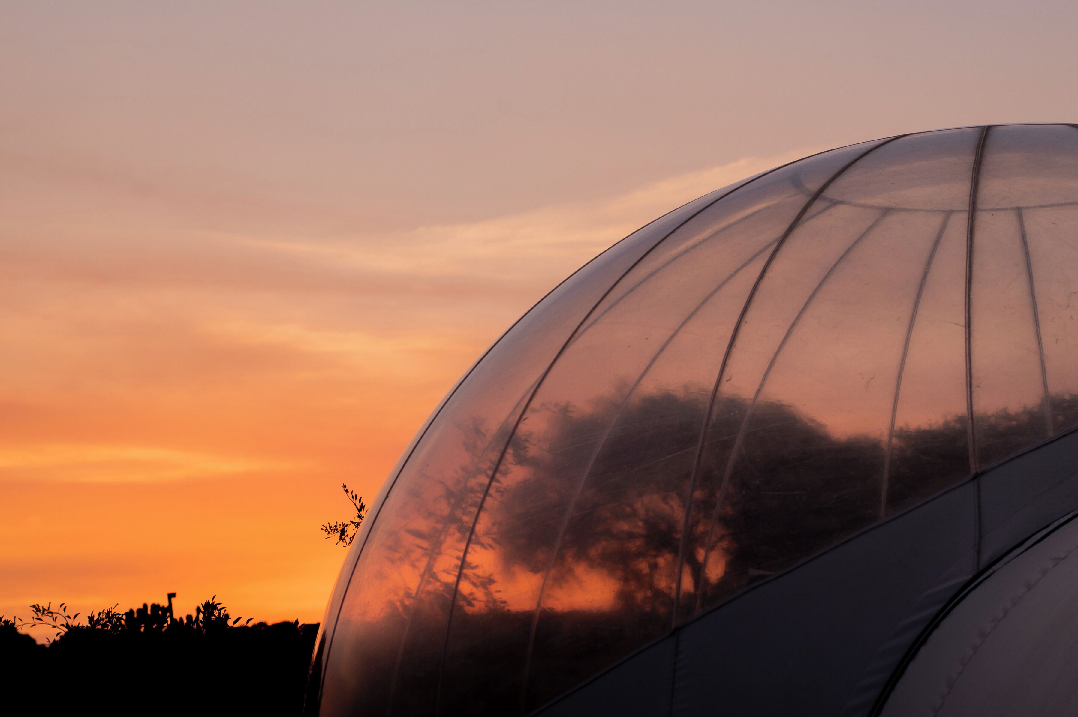 A transparent dome structure with a sunset view.