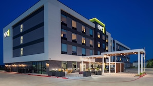 A modern hotel with a two-story structure, large windows, and a covered outdoor area with seating. - Home2 Suites By Hilton Bastrop, Tx (Bastrop)