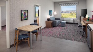A hotel room with a dining area, a sofa, a TV, and a window with a view of the countryside. - Home2 Suites By Hilton Bastrop, Tx (Bastrop)