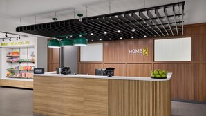 Una moderna zona de recepción de hotel, con un mostrador de madera, un quiosco digital informativo y una exhibición de snacks.