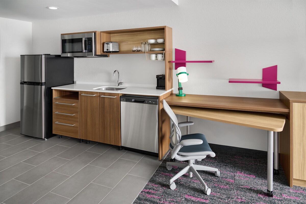 A compact kitchen with a built-in microwave, refrigerator, and dishwasher.