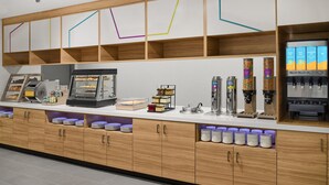 Un café moderno con un mostrador de madera, máquinas de café y un dispensador de zumos.