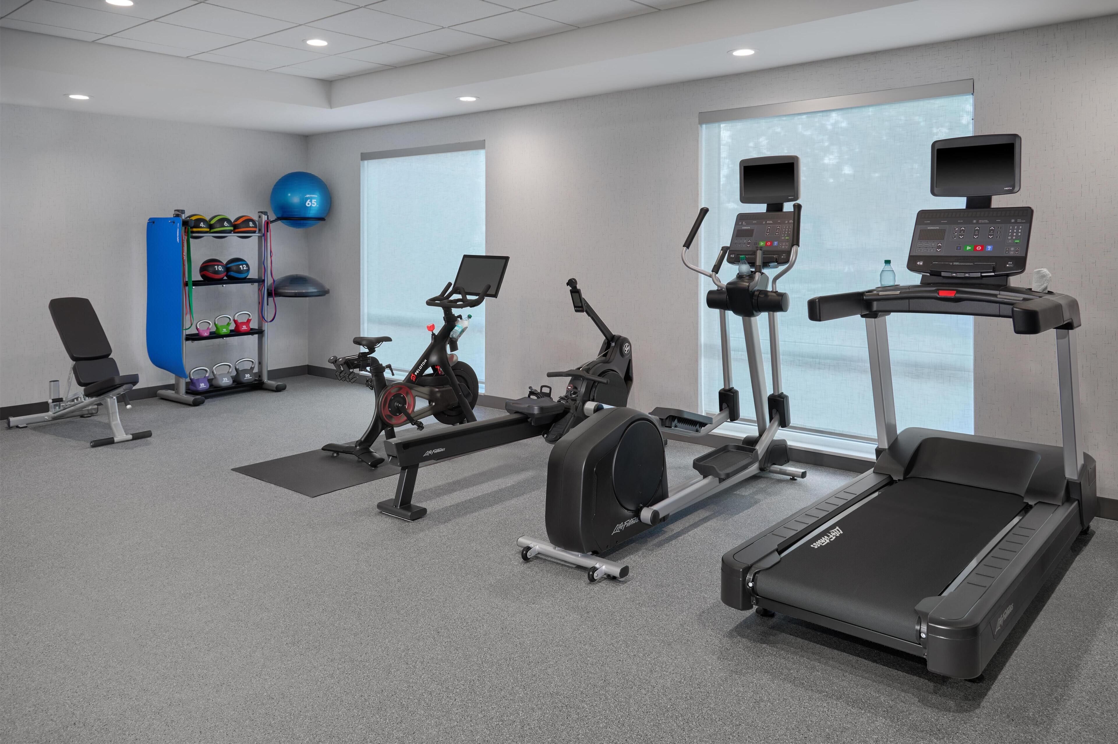 A gym with cardio machines, weightlifting equipment, and a rowing machine.