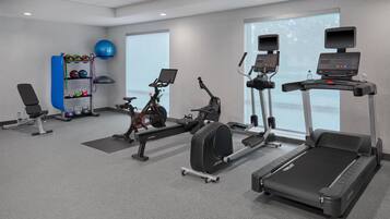 A gym with cardio machines, weightlifting equipment, and a rowing machine.