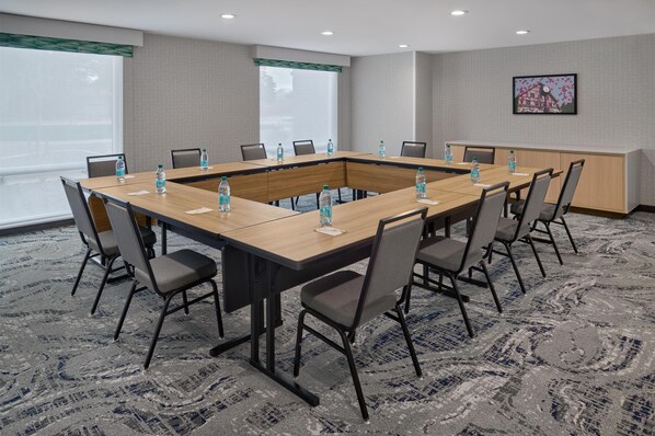 A conference room with a large rectangular table, chairs, water bottles, and a carpeted floor.