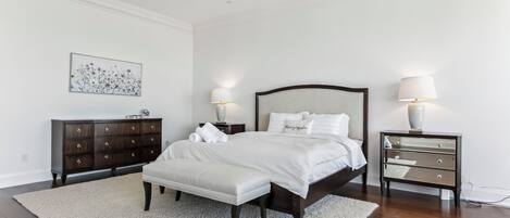 A bedroom with a large bed, two bedside tables, a dresser, and a rug.