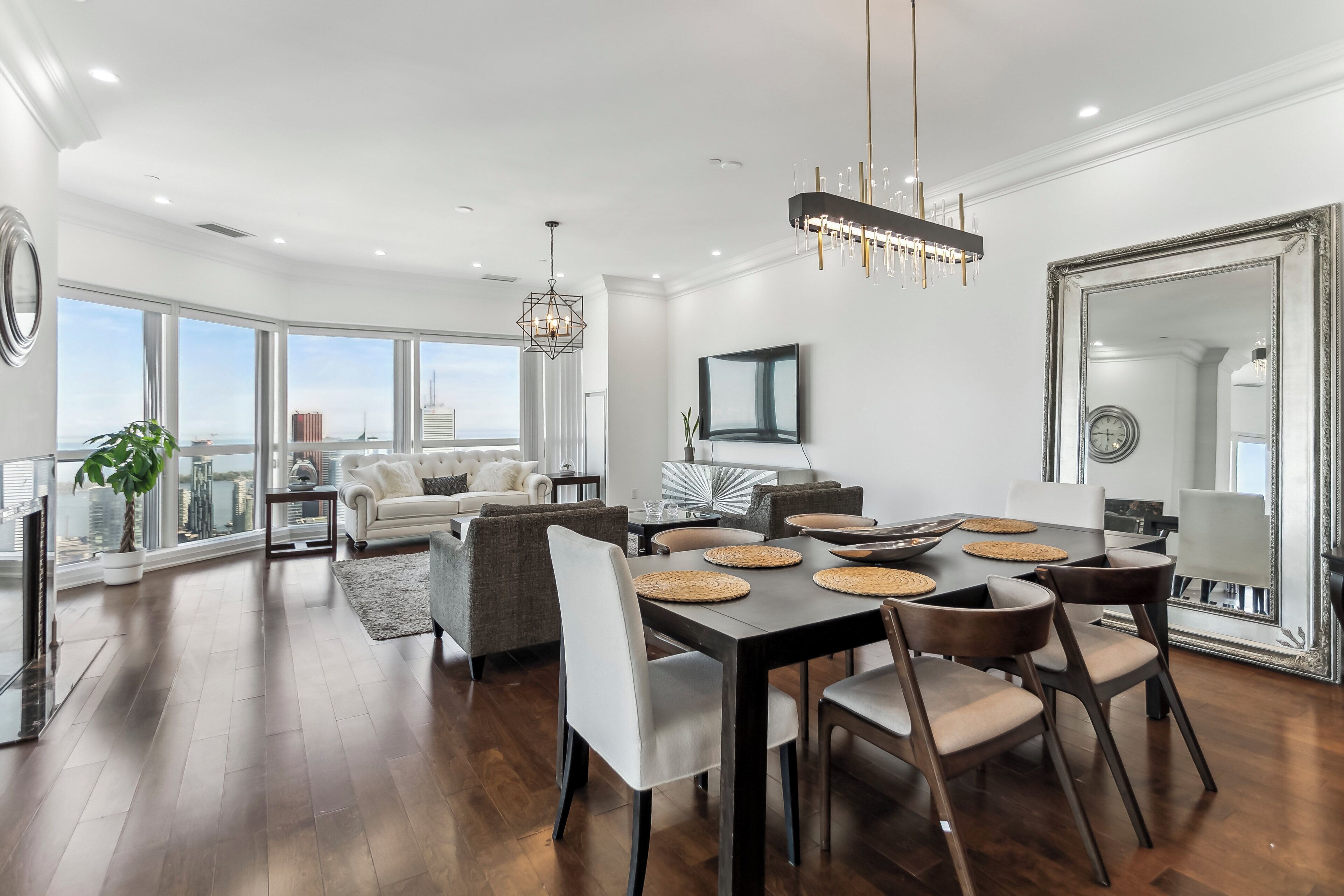 A spacious living area with a dining table, modern furniture, and large windows offering a city view.