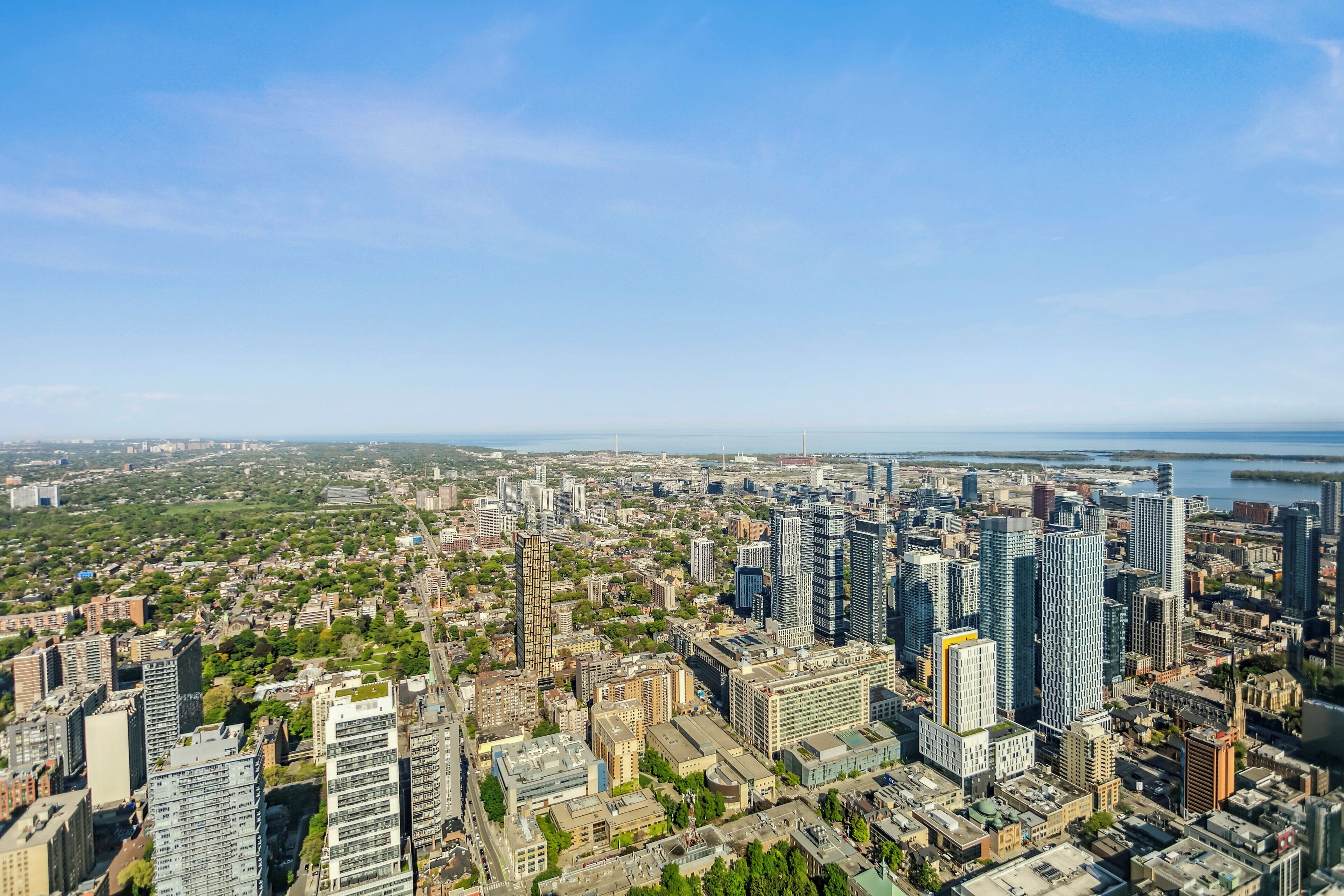 A cityscape with high-rise buildings, a mix of residential and commercial structures, and a body of water in the distance.