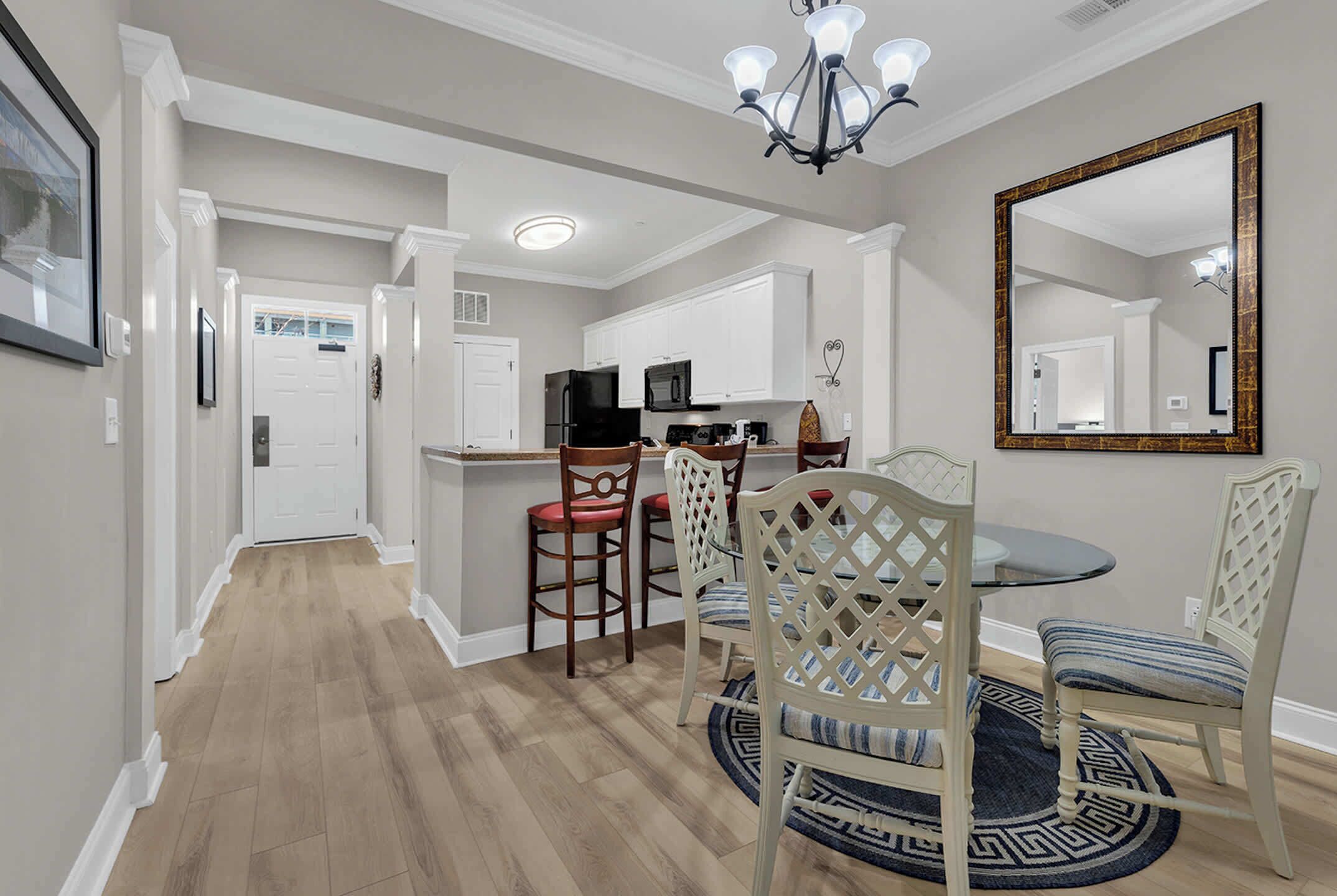 A modern kitchen with white cabinetry, a black refrigerator, and a dining area with a round table and chairs.